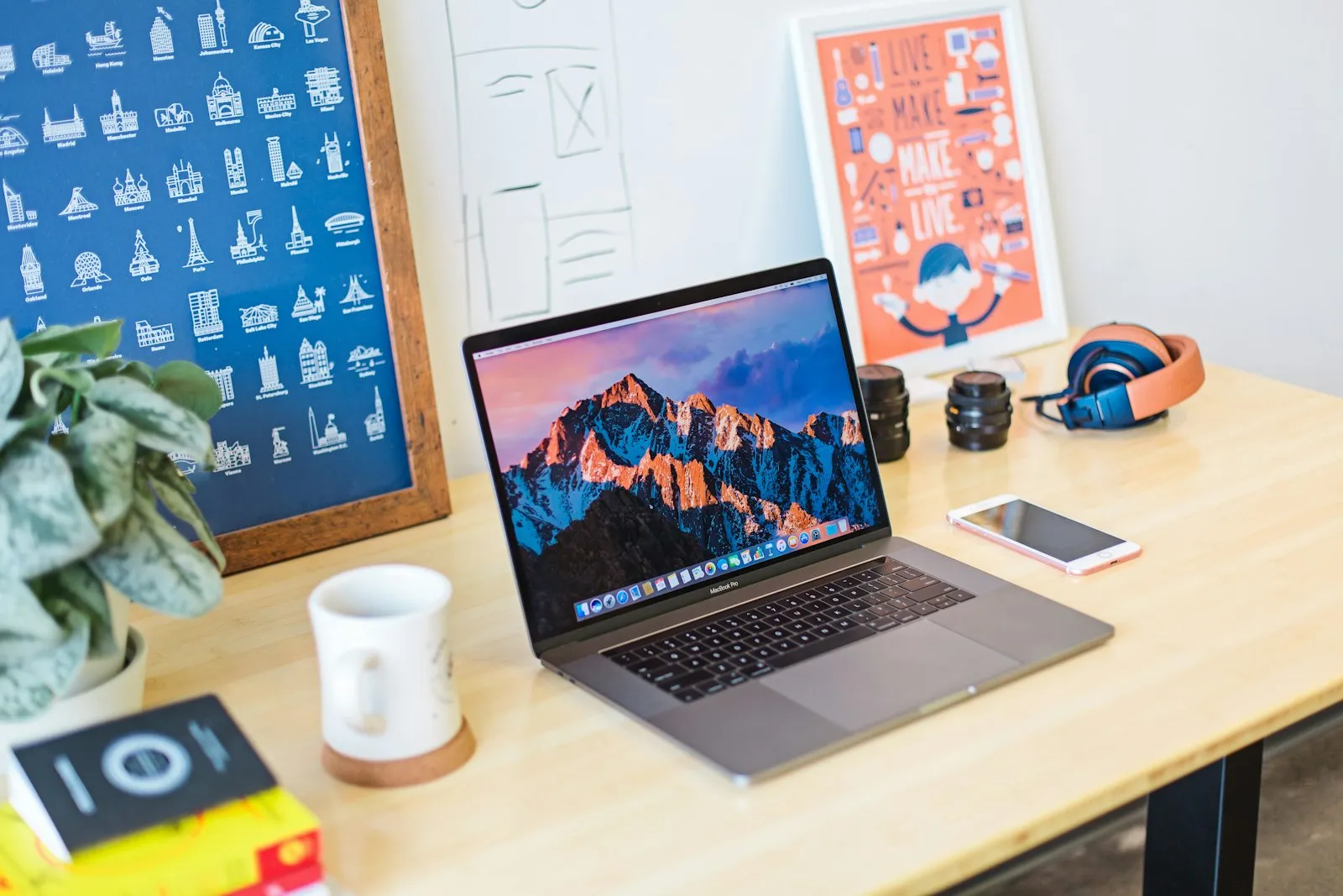 A designer’s desk with a laptop, framed posters and a plant, where design and code meet.