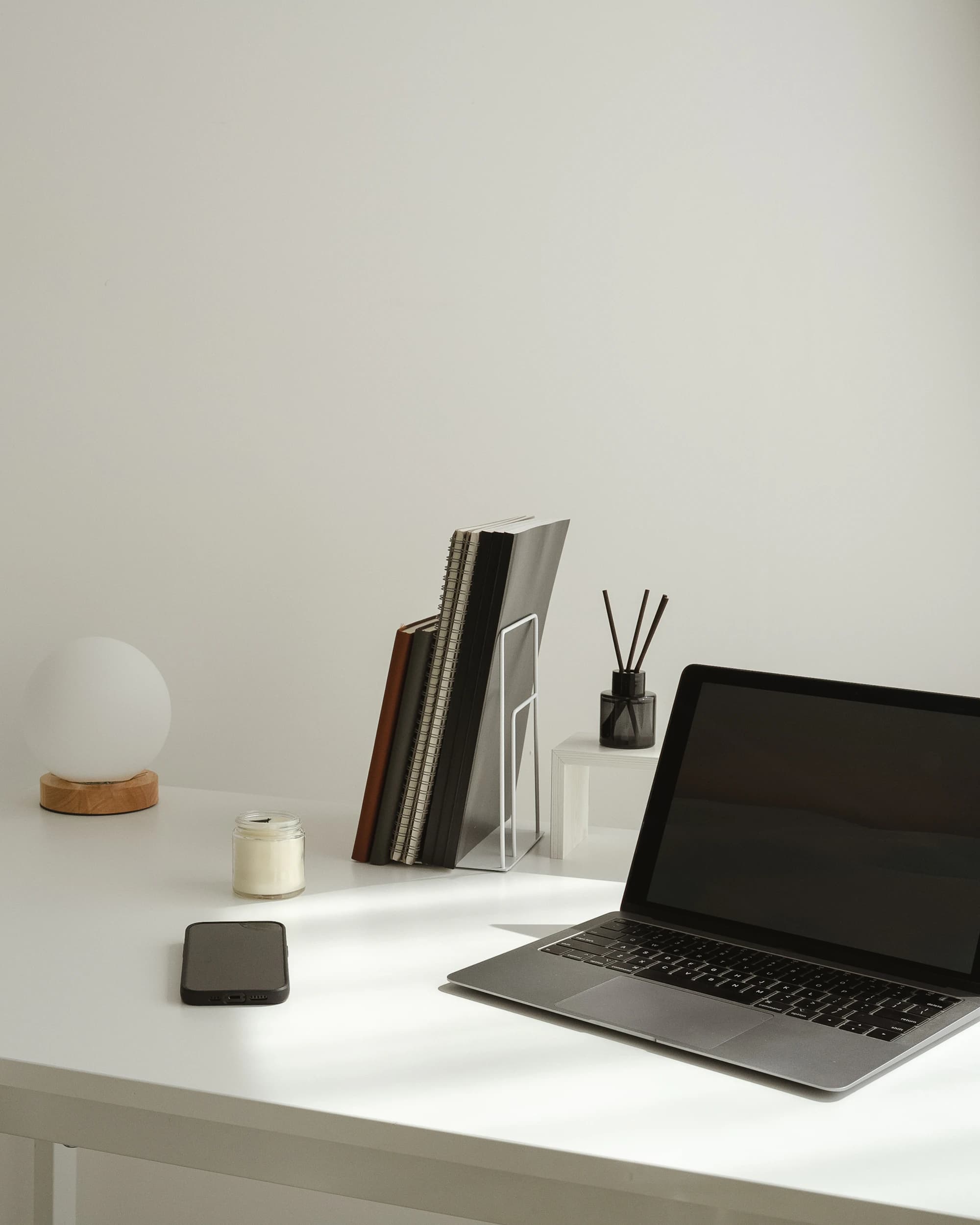 A minimal desk with a laptop and a lamp in soft morning light.